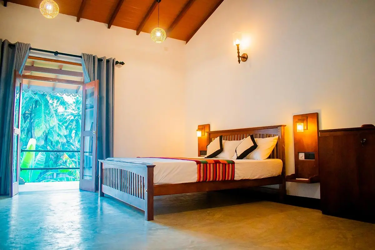 Bedroom under a pitched timber ceiling with doors open to the greenery