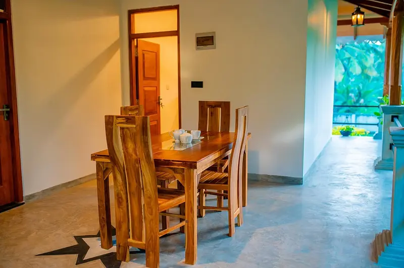 Dining area with teak table and chairs next to the bedroom