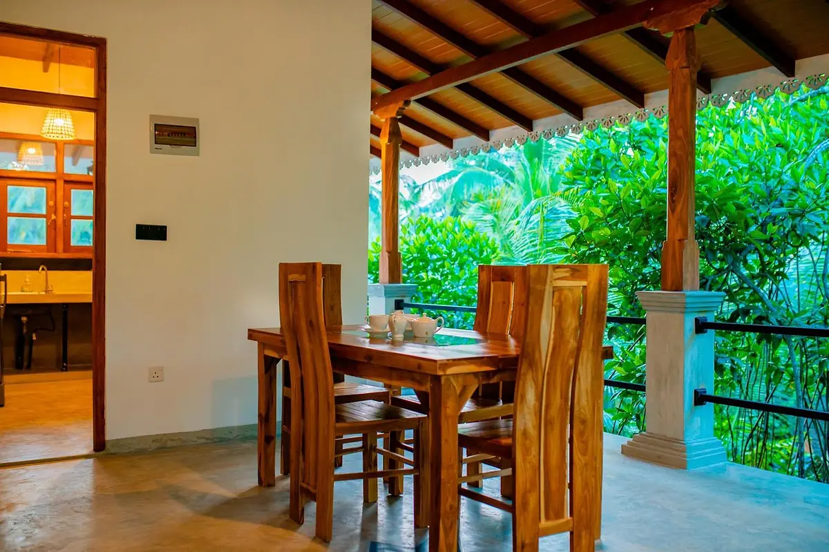 Teak dining set beside the open veranda with garden views