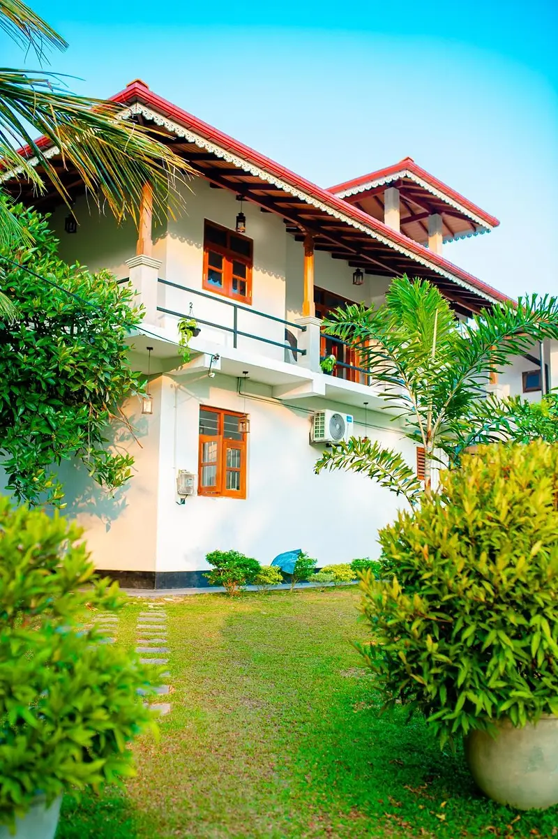 Villa 4Eyes by day, white walls and a terracotta roof framed by garden greenery
