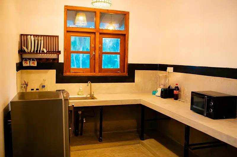 Kitchen with sink, fridge and microwave under a teak-framed window