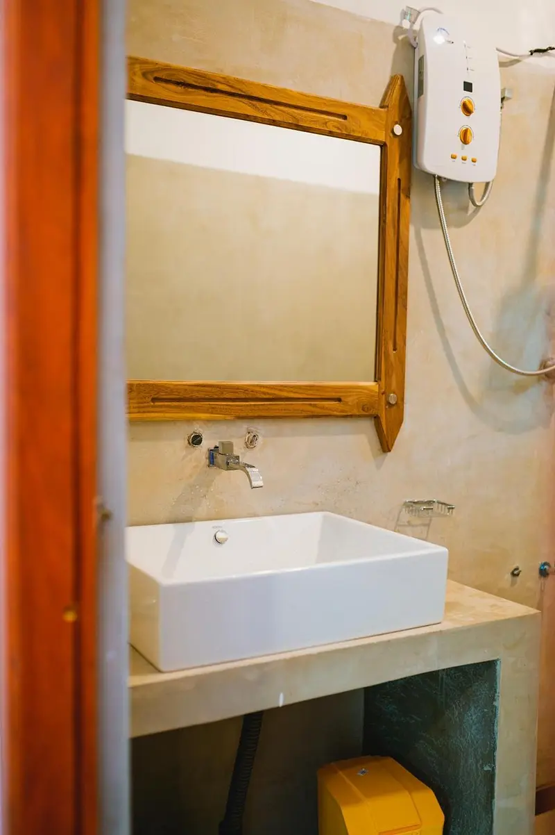 Bathroom basin with a timber-framed mirror and hot-water heater
