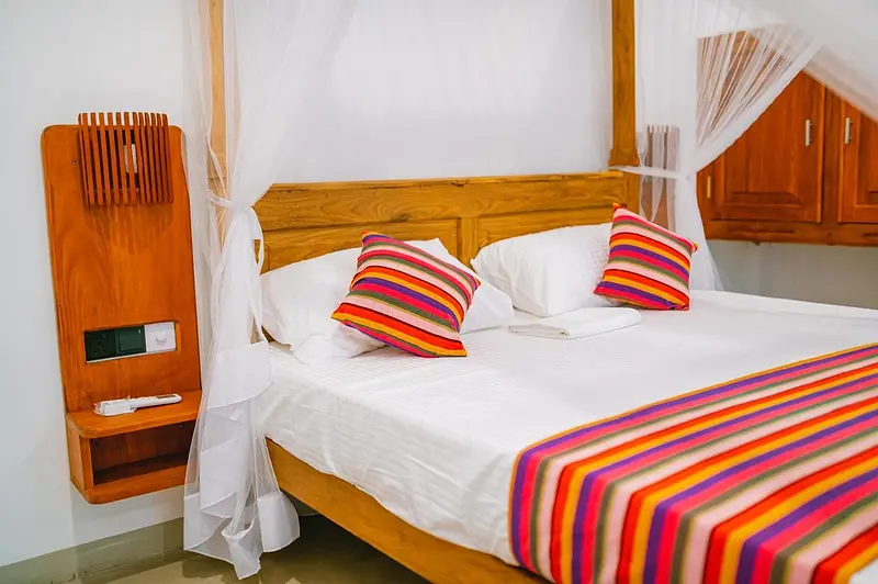 King bed with striped Sri Lankan cushions and throw