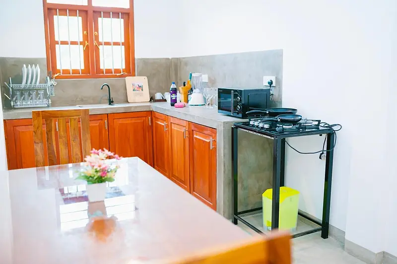 Kitchen and dining table with gas hob, microwave and kettle