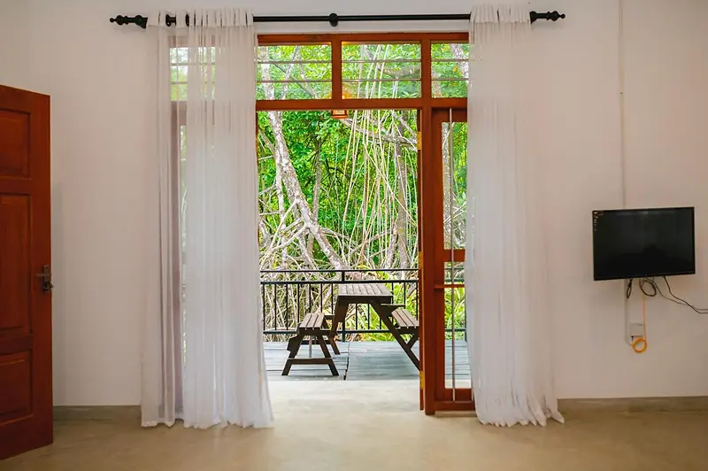 Double doors opening from the room onto the mangrove deck, with a wall-mounted TV