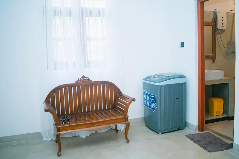 Carved teak sofa beside the washing machine and bathroom door