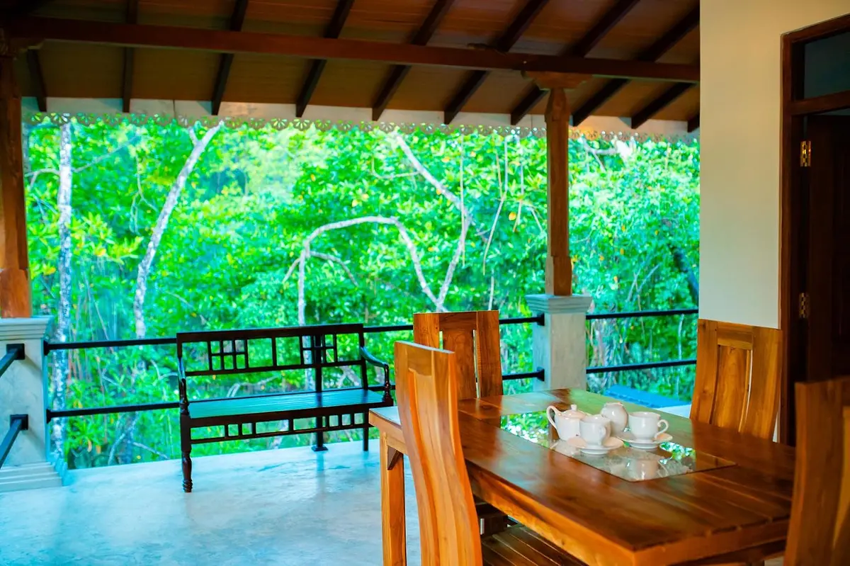 Covered upstairs veranda with a teak dining table looking out over the mangroves