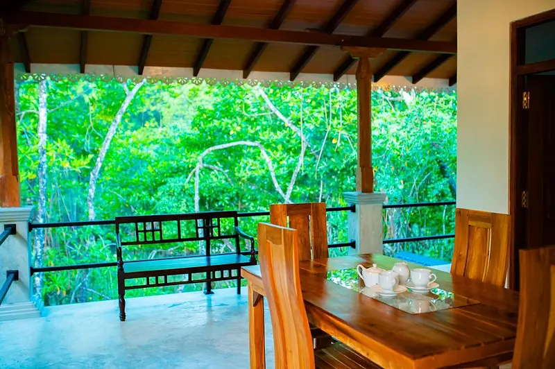 Covered upstairs veranda with a teak dining table looking out over the mangroves