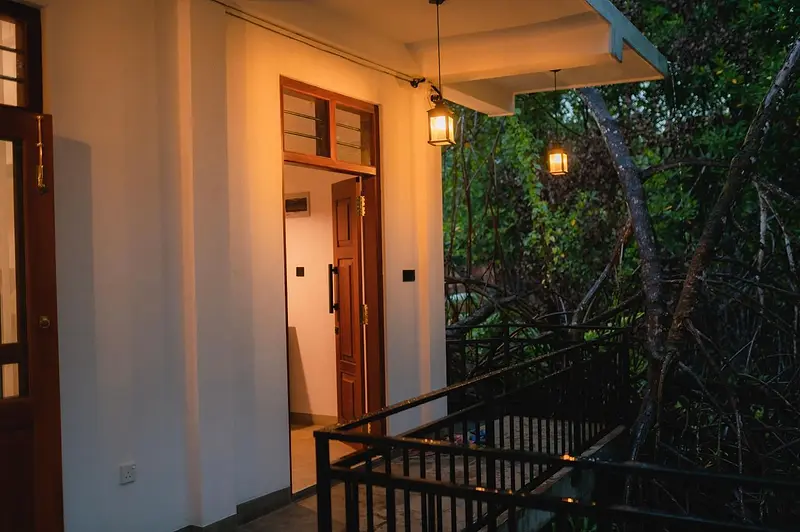 Ground-floor walkway lit by lanterns at night, edged by mangroves